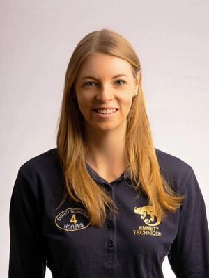 Das Bild zeigt eine lächelnde Frau mit langen Haaren in einem "EMMET TECHNIQUE"-Shirt.